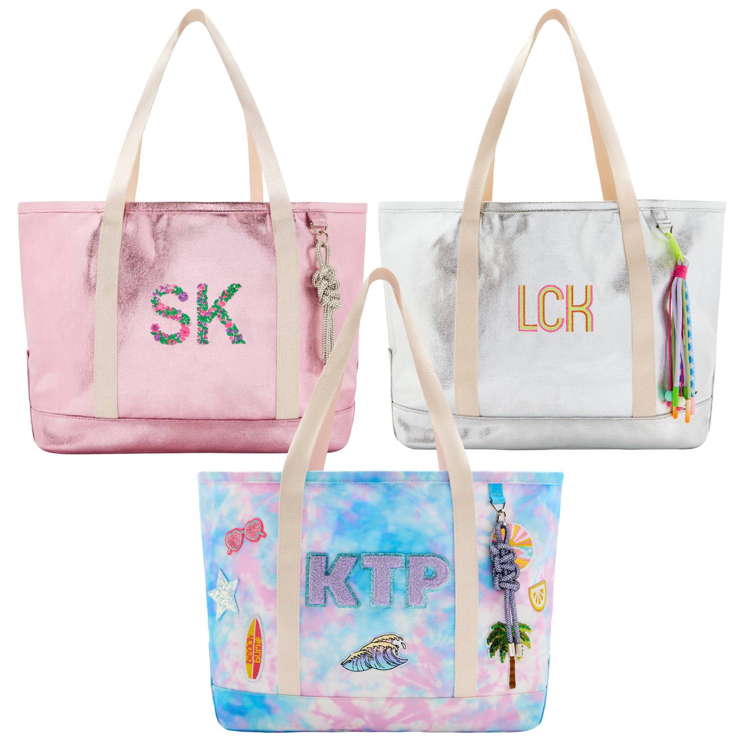 Three personalized kids tote bags with embroidered initials and custom patches — pink metallic, silver metallic and tie dye designs on a white background