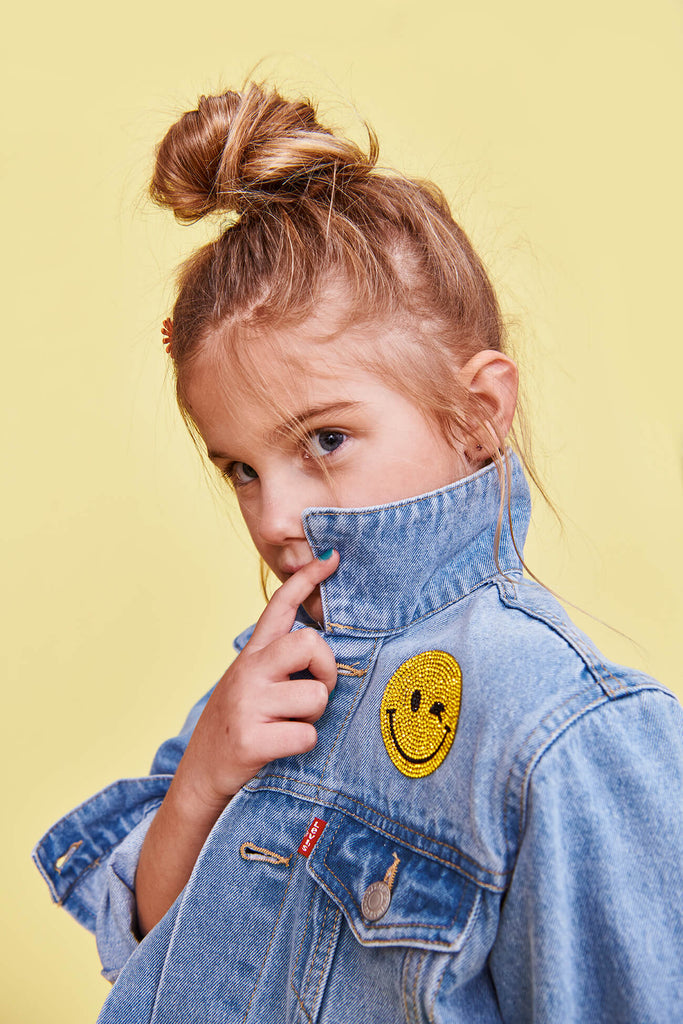 Girl in customizable jean jacket with crystal smiley emoji patch