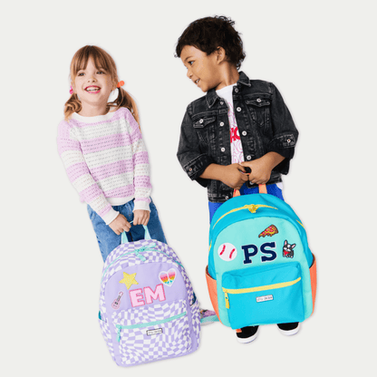 Two children holding colorful backpacks with cartoon designs on a white background