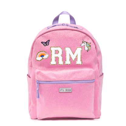 Pink backpack with 'RM' initials, a rainbow, butterfly, and unicorn patch on a white background.