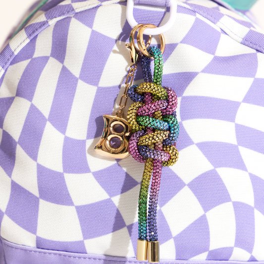 Colorful keychain  bag charm with a decorative design on a purple and white checkered duffel