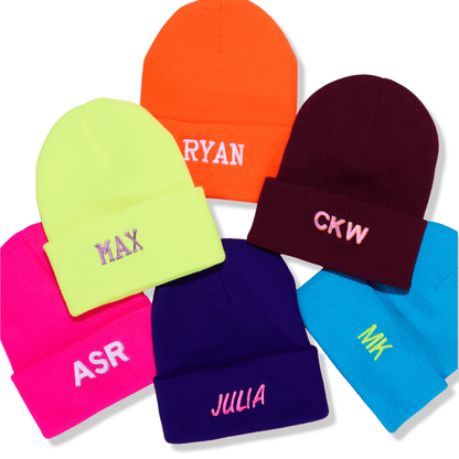Colorful kids beanies with embroidered names on a white background
