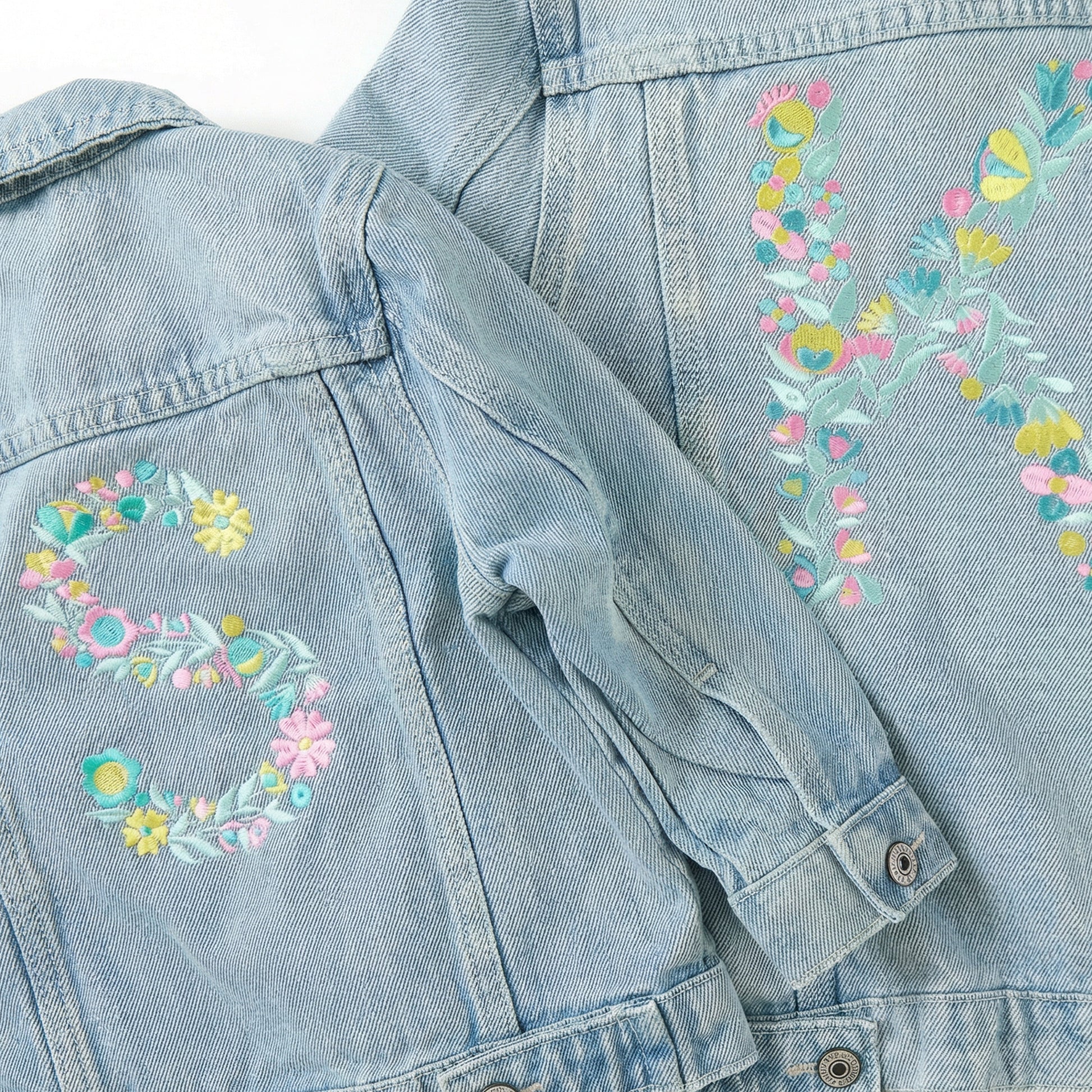 Light blue denim jacket with floral embroidery on a matching fabric background