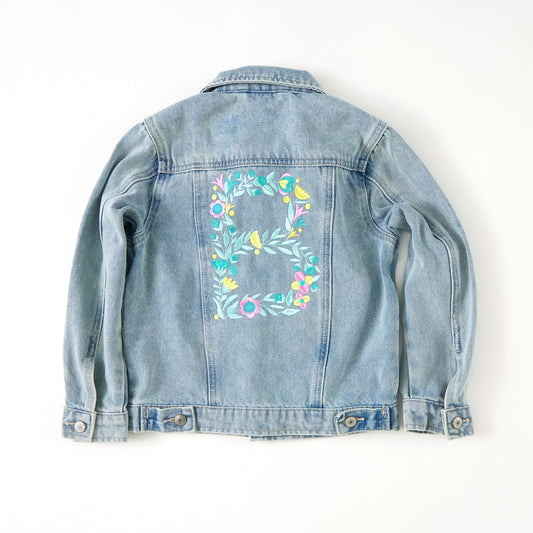 Denim jacket with floral embroidery on a white background