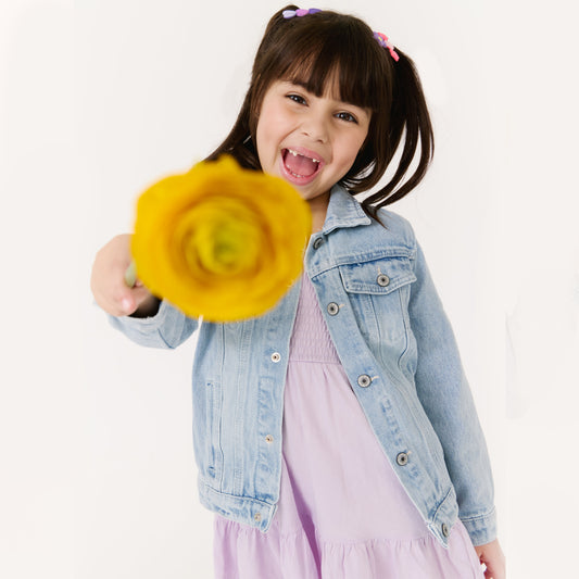 Child holding a yellow flower against a white background