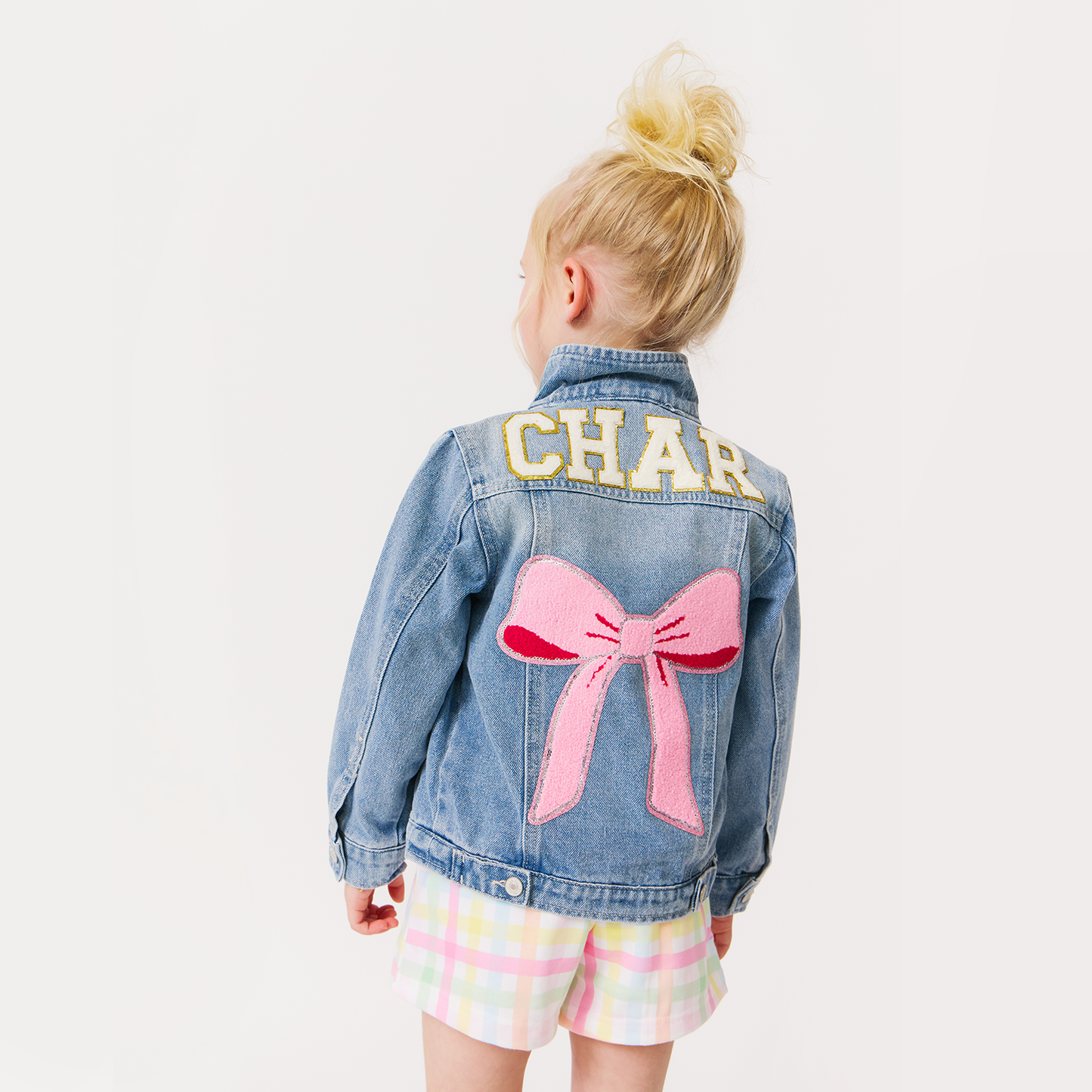 girl wearing a custom denim jacket with a pink bow patch 