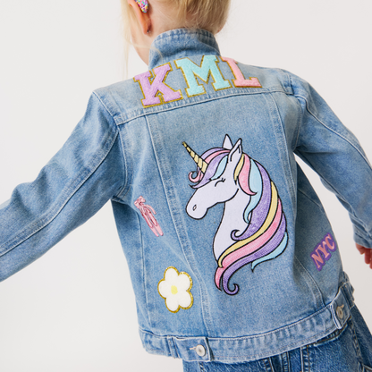 a girl wearing a customized denim jacket with various colorful patches on it. The jacket is adorned with different designs and monogrammed