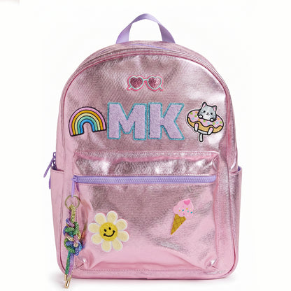 Personalized metallic pink kids backpack with custom initials and colorful patches including a rainbow, smiley flower, cat, ice cream cone and heart sunglasses. Features a front zip pocket, side pockets and spacious storage for school, camp and travel.