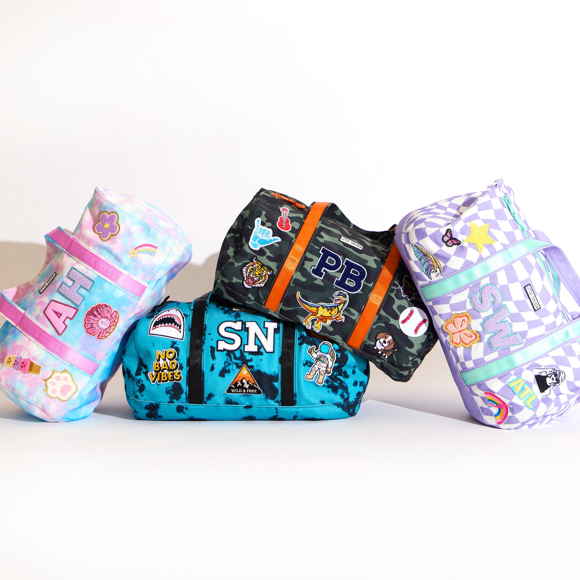 Four colorful duffel bags with various designs and patches  on a white background