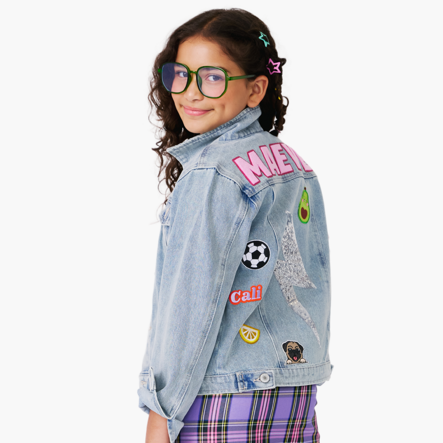 Young girl wearing a personalized denim jacket with  patches on a white background