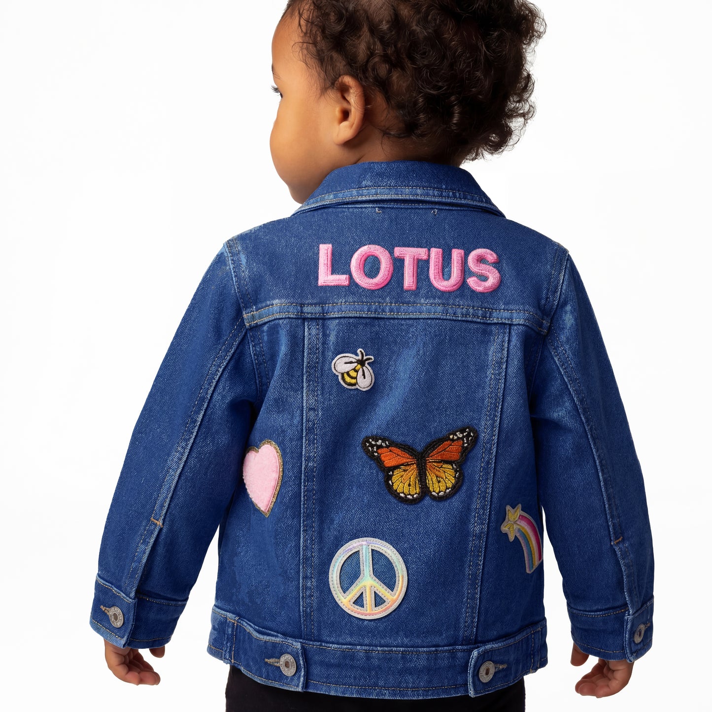 baby wearing a denim jacket with patches and 'LOTUS' branding on a white background