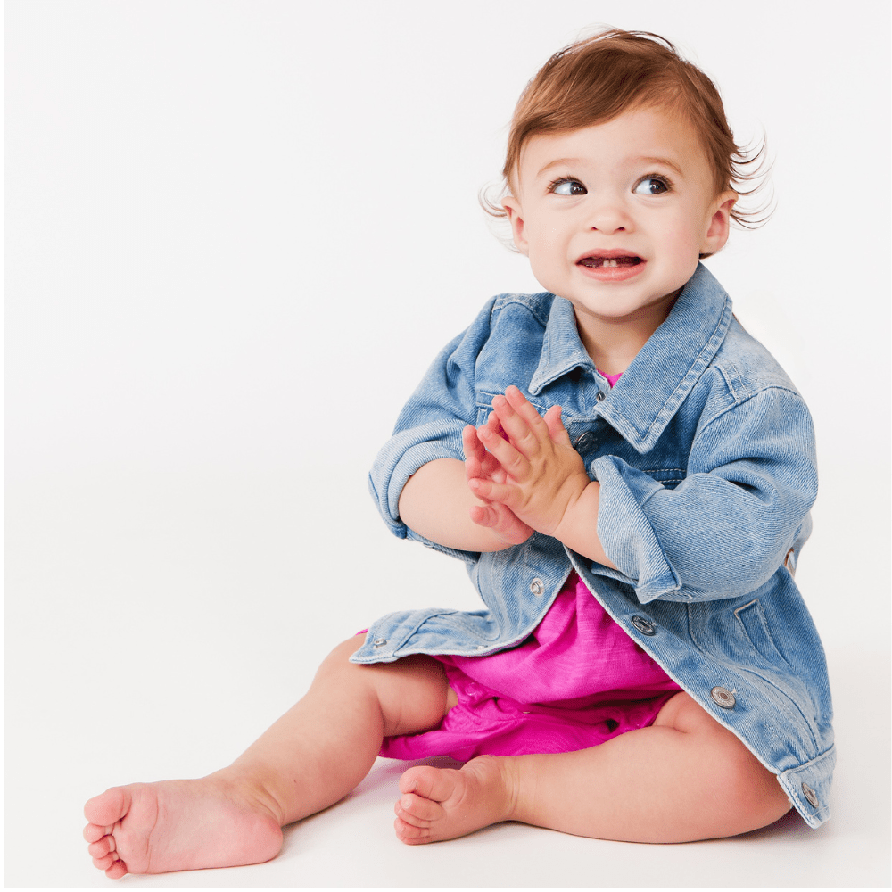Baby wearing a denim jacket and pink outfit on a white background