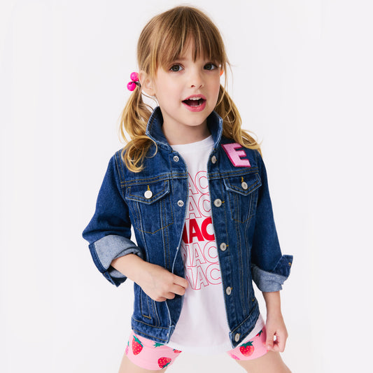 Young girl wearing a denim jacket with pink letters on a white background