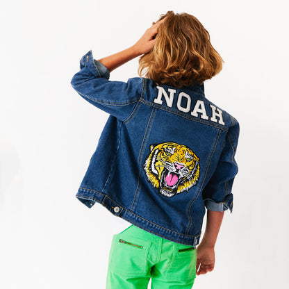 a child wearing custom denim jacket with various patches on it. tiger patch