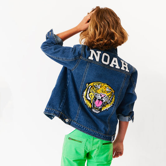 a child wearing custom denim jacket with various patches on it. tiger patch