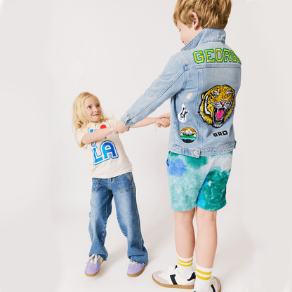 Two children wearing denim jcustom ackets with patches on a white background