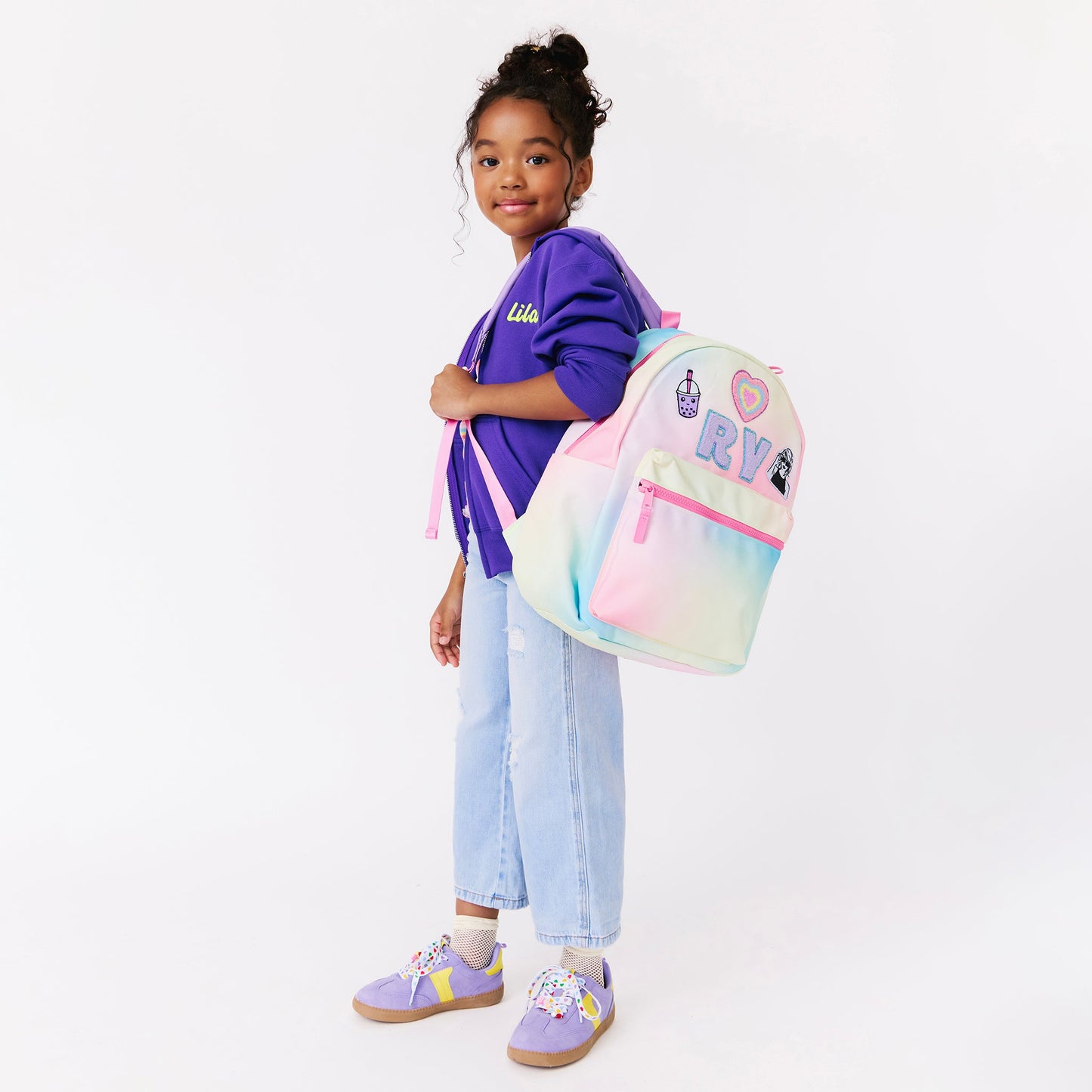 girl holding a rainbow backpack. personalized backpack