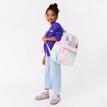 girl holding a rainbow backpack. personalized backpack