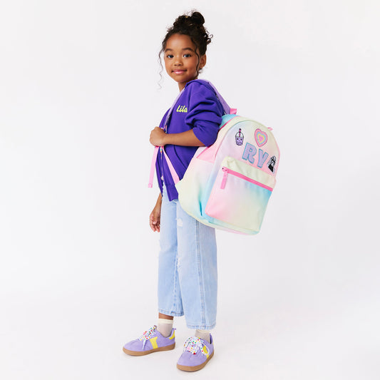 girl holding a rainbow backpack. personalized backpack