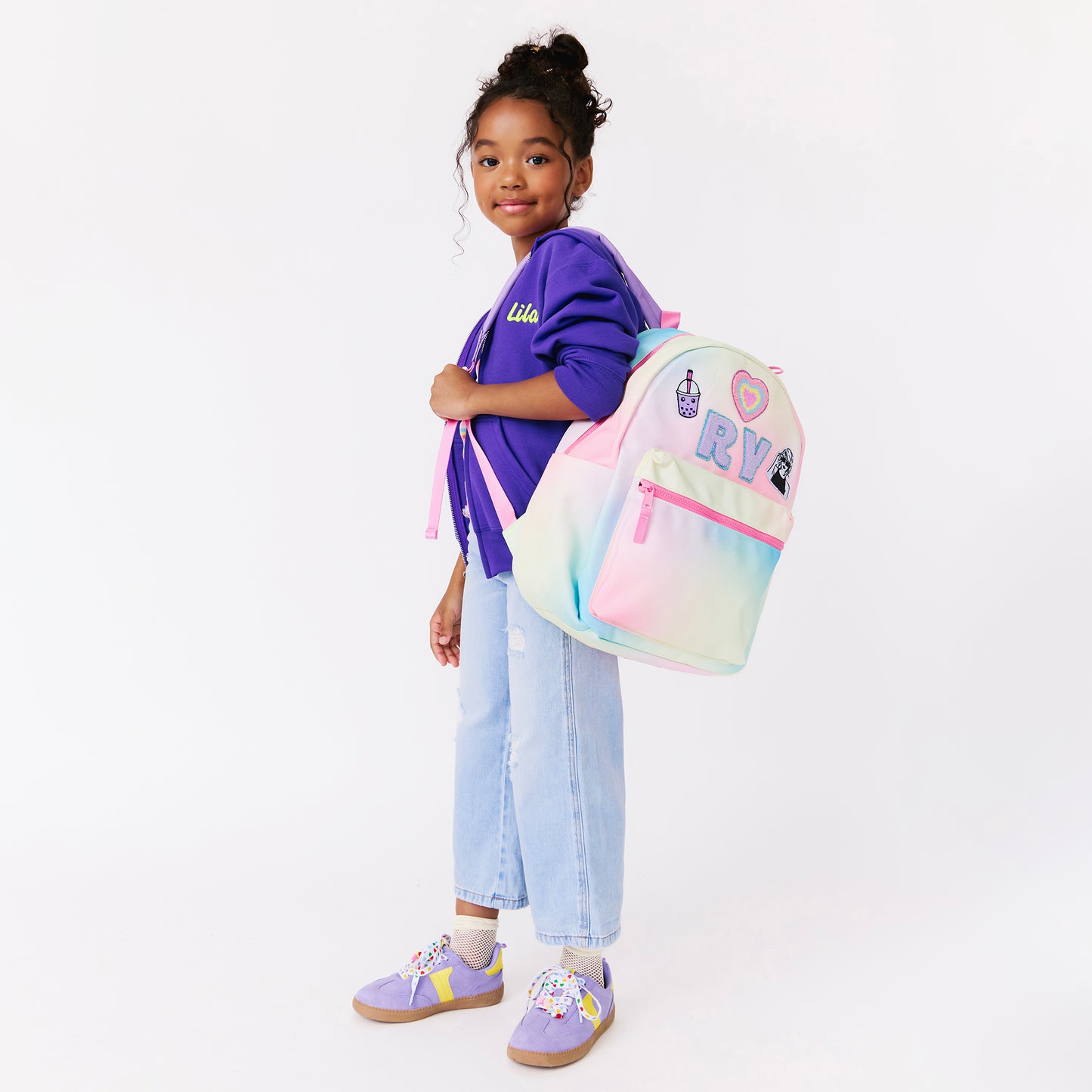 girl holding a rainbow backpack. personalized backpack
