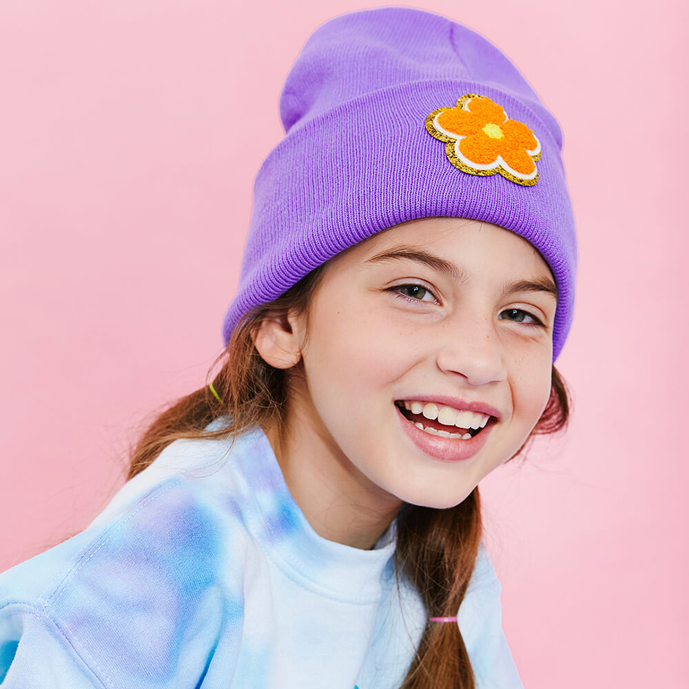 Girl in purple beanie customized with orange daisy patch