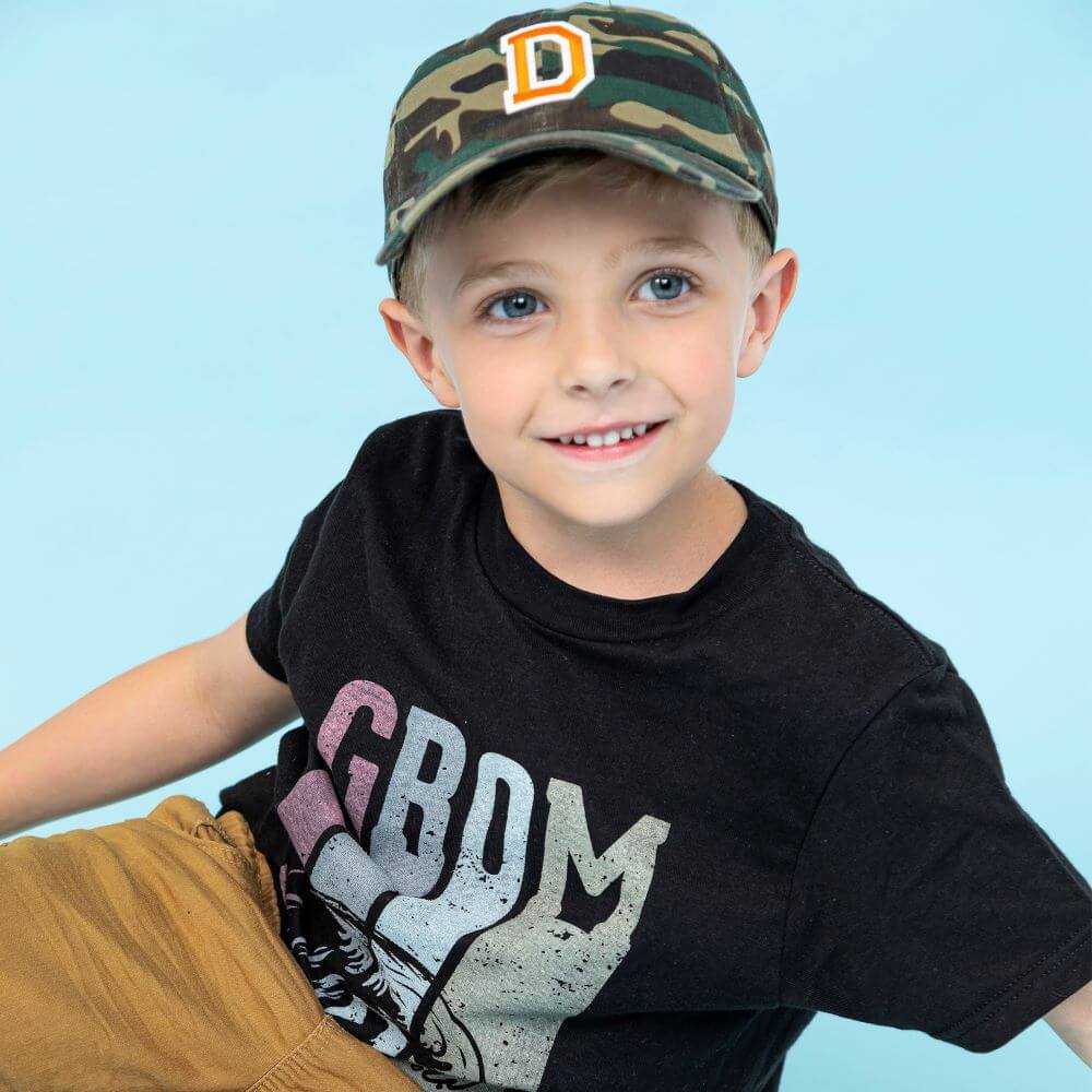 boy in surfing GROM t-shirt and camo trucker hat with custom patch